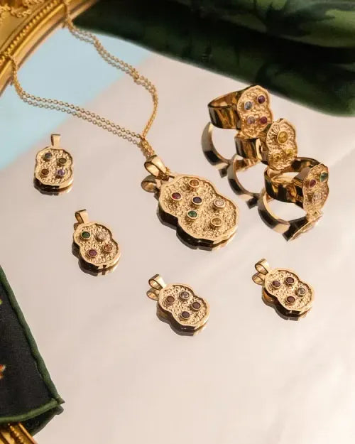 The Nugget collection laid out together: pendants, rings and earrings beside a gold mirror