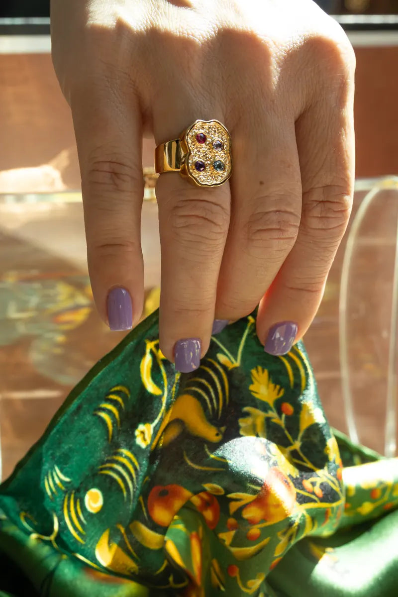 A stone-set gold ring worn over green printed silk