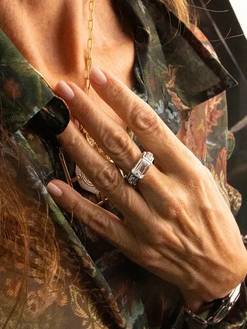 A hand wearing the East–West ring, photographed in low light