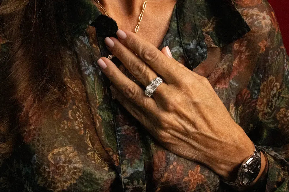 Rings worn on crossed hands, photographed over an embroidered jacket